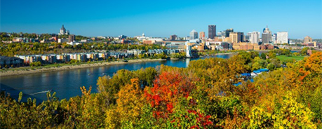 View of campus along the Mississippi River's edge, Minneapolis skyline in the distance