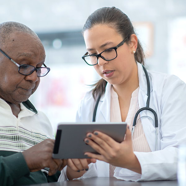 Senior man speaks with a health care provider while looking at a digital display